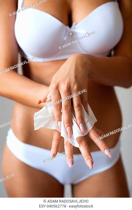 Young woman with long nails clean hands with wet wipes, body breast lingerie panties in blurred background
