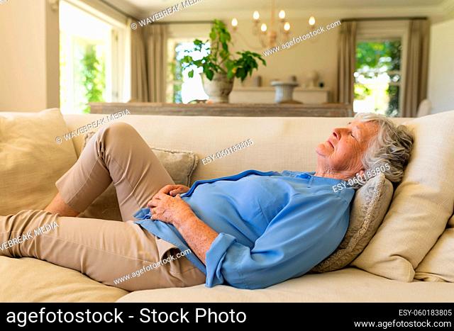 Senior caucasian woman lying on sofa with eyes closed