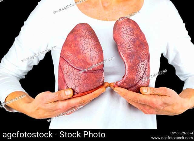 Woman holds models of two lungs at white body isolated on black background