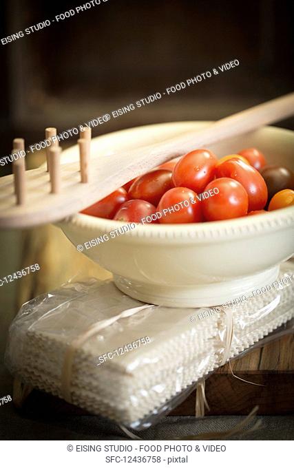 An arrangement of cherry tomatoes, a pasta fork and a pack of pasta
