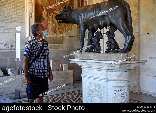A visitor with a protective mask admires the bronze Capitoline Wolf in the Sala Lupa of the Capitoline Museums during the first weekend after the recent partial...