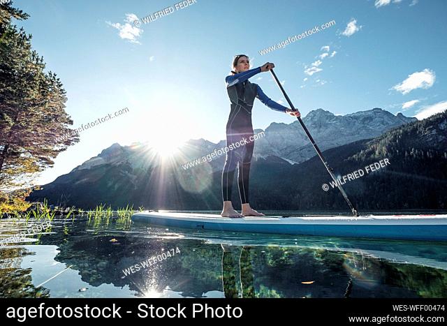 Germany, Bavaria, Garmisch Partenkirchen, Young woman stand up paddling on Lake Eibsee