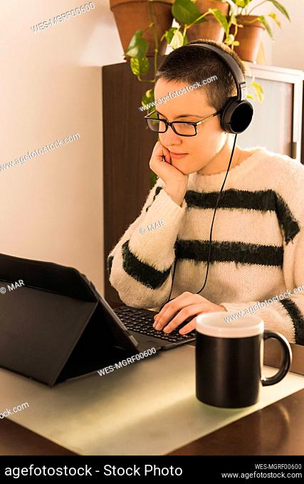 Businesswoman wearing headphones using tablet PC at office