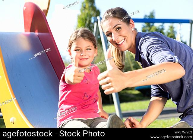 Mother and little girl chuting at adventure playground in park
