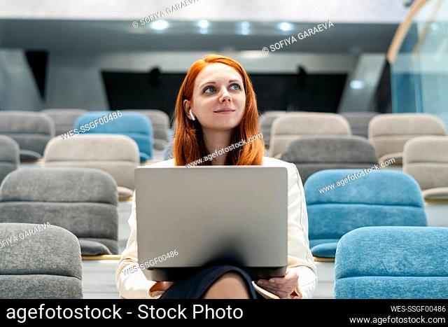 Thoughtful businesswoman with laptop at auditorium in office