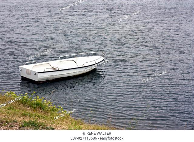 White rowboat anchored near meadow in adriatic