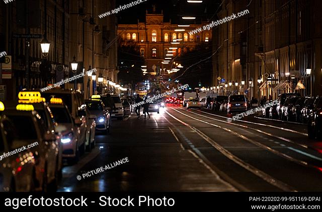 02 February 2022, Bavaria, Munich: Car driving along Maximilianstrasse. In the background you can see the Maximilianeum, seat of the Bavarian Parliament