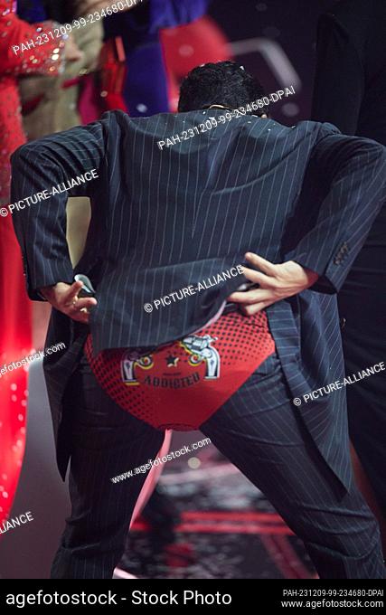 08 December 2023, Berlin: Coach Giovanni Zarrella receives a pair of underpants as a gift in the final of the Sat.1 show ""Voice of Germany"" and puts them on...
