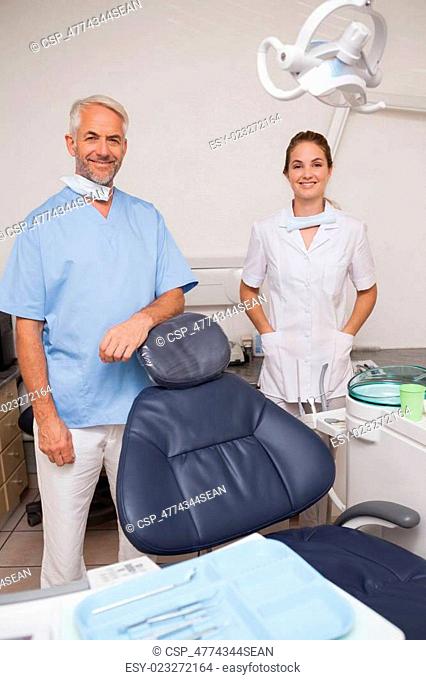 Dentist and assistant smiling at camera inviting you to the chai