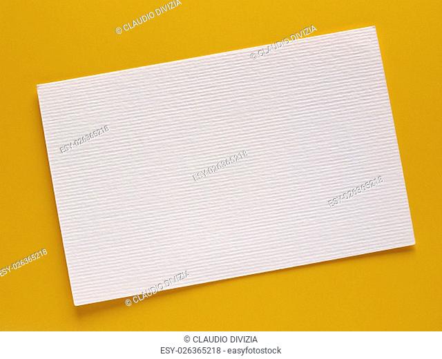 Blank paper tag label or sticker with copy space - flat lay on yellow desktop background