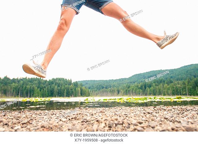 A woman jumping beside a lake in Bowen Island, British Columbia, Canada