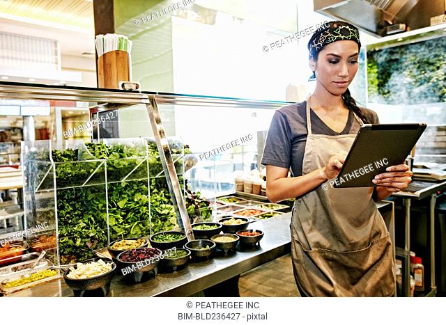 Mixed Race food court worker using digital tablet