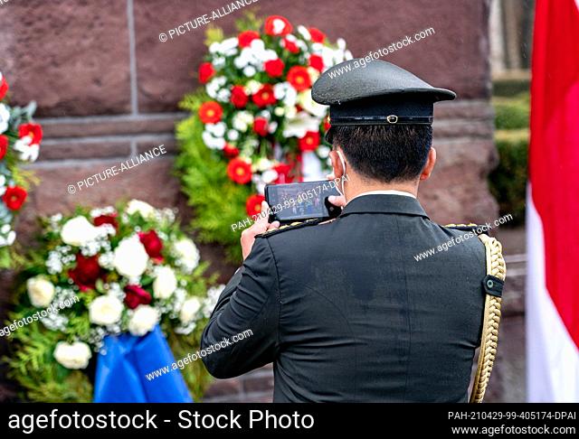 29 April 2021, Schleswig-Holstein, Heikendorf: An Indonesian officer photographs the wreath laid for the commander and crew of the doomed Indonesian submarine...