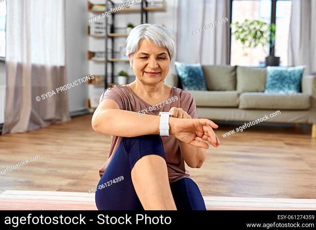 smiling senior woman with fitness tracker at home