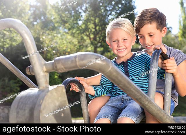 Two boys using digger on adventure playground in park