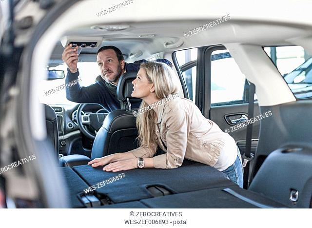 Couple examining new car at car dealership