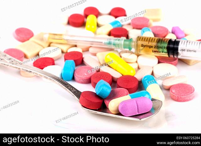 Colored Pills with silver spoon on white table