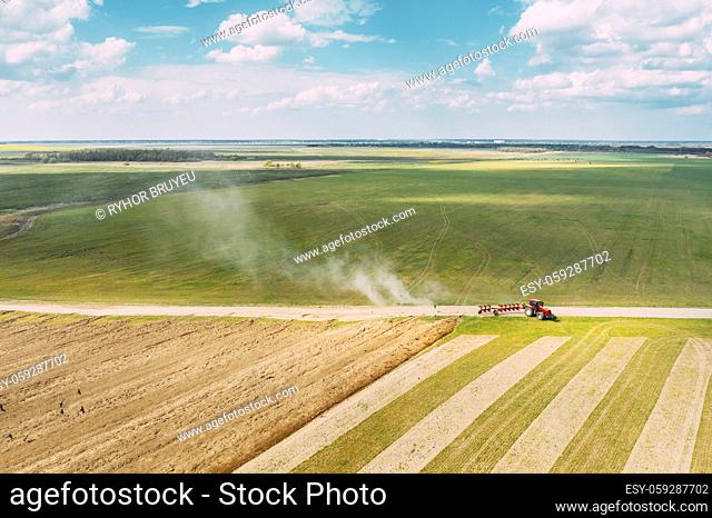 Aerial View. Tractor Plowing Field In Spring Season. Beginning Of Agricultural Spring Season. Cultivator Pulled By A Tractor In Countryside Rural Field...