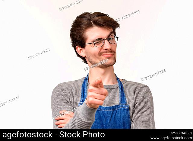 Close-up portrait of cheeky smiling handsome man inviting person start career at his coffee shop, pointing camera and wink hinting friend made good point