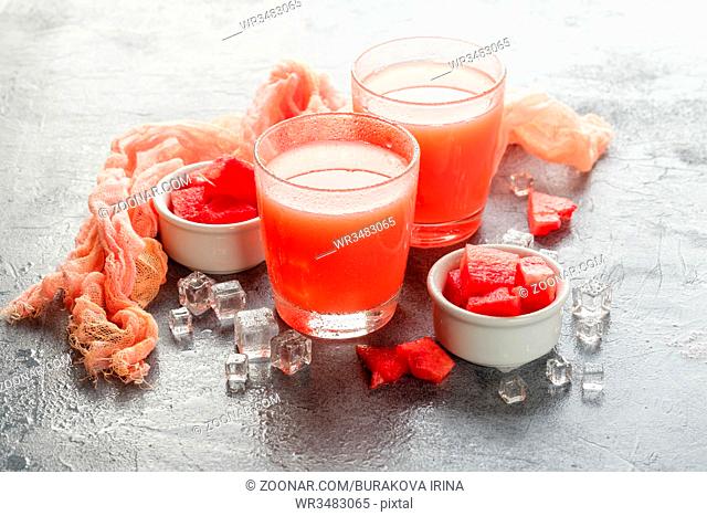 Watermelon drink with ice in glasses on gray concrete background
