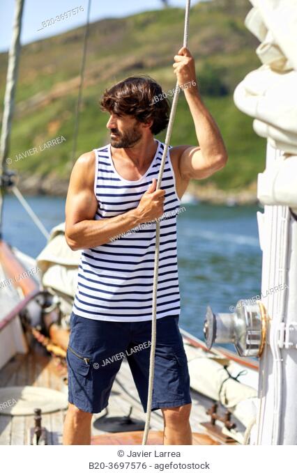 Young man with sailor clothes, Sailor hoisting the sails, Sailboat, Port of Pasaia, Gipuzkoa, Basque Country, Spain, Europe