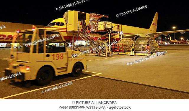 29.08.2018 Saxony, Schkeuditz: A tractor pulls trailers with freight containers over Leipzig/Halle Airport at night. The DHL hub at Leipzig Airport went into...