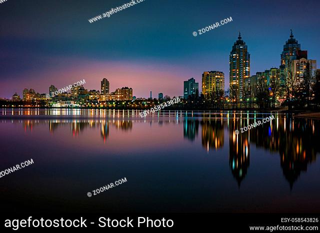 Night view of modern buildings in the Obolon district of Kiev, Ukraine, close to the Dnieper River, The lights reflect on the calm water