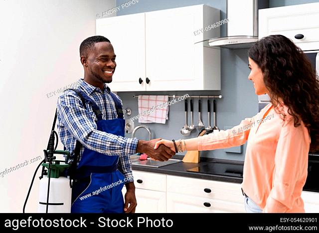 Happy Woman And Young Pest Control Worker Shaking Hands To Each Other In Kitchen Room