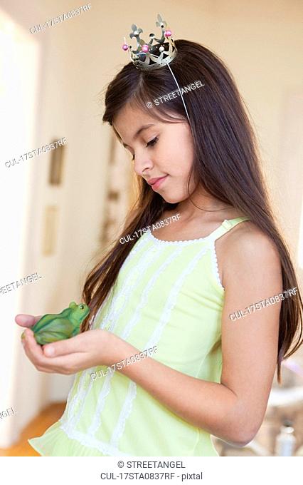 girl wearing crown holding toy frog