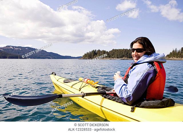 Woman sea kayaking in Kachemak Bay, near Homer, South-central Alaska; Alaska, United States of America