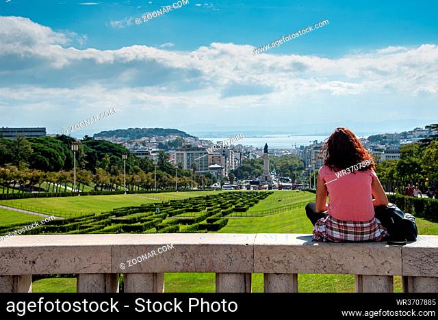 Unrecognized tourist woman in the Eduardo VII park, looking at Lisbon's cityscape in Portugal Europe