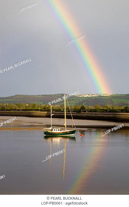 Rainbow over moored boat on river Deganwy. Conwy is the only town in Wales that still has a complete circuit of town walls and in Britain