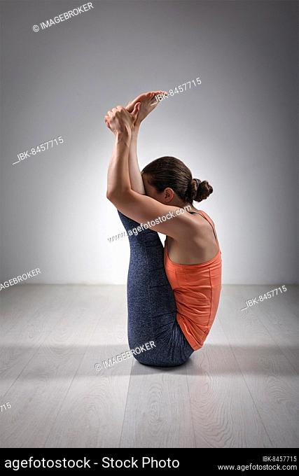 Sporty fit woman practices yoga asana Urdhva mukha paschimottanasana, upward facing intense west stretch