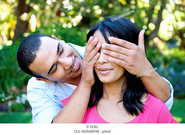 Young man covering woman's eye