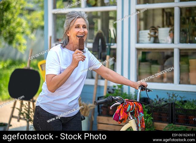 Eating ice-cream. A happy mature woman eating ice-cream and looking enjoyed