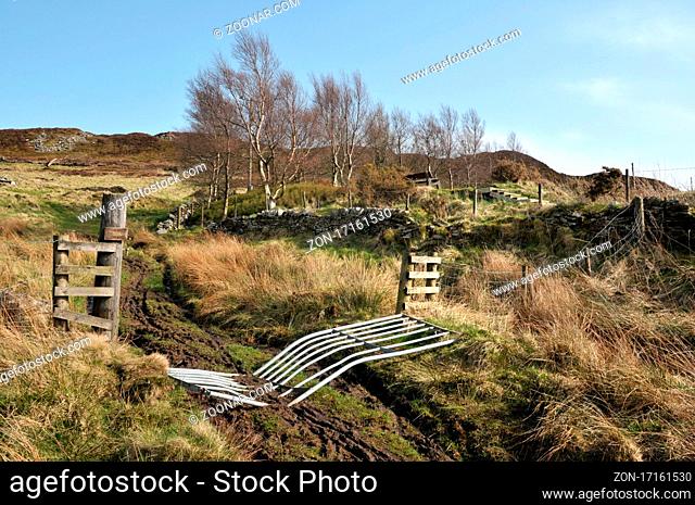 high pennine farmland with a broken gate across a pathway leading to midgley moor in calderdale west yorkshire