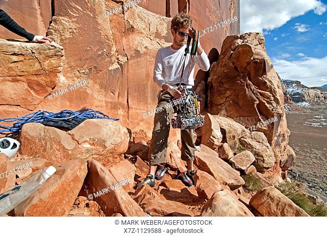 Man sorting gear to rock climb a route called Amaretto Corner on Super Crack Buttress at Indian Creek Canyon in southern Utah
