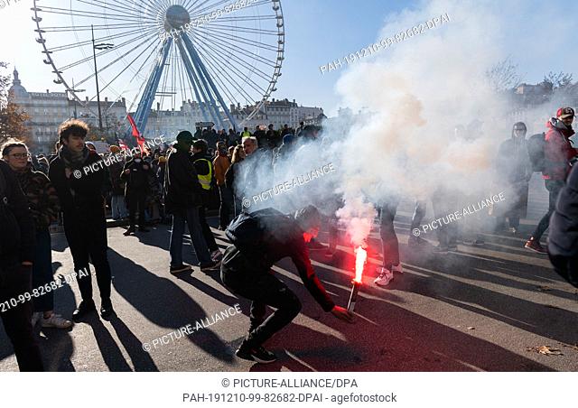 10 December 2019, France (France), Lyon: A demonstrator ignites pyrotechnics during a demonstration in the context of strikes and protests against the pension...