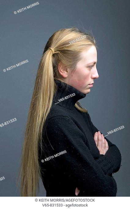 side on profile view of teenage girl with her hair in pigtails looking moody, stroppy, introverted