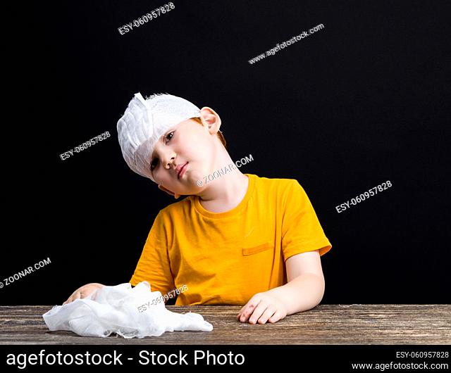 a beautiful boy with red hair with a damaged head bandages himself with a medical bandage, a boy with medical equipment during self-treatment, closeup