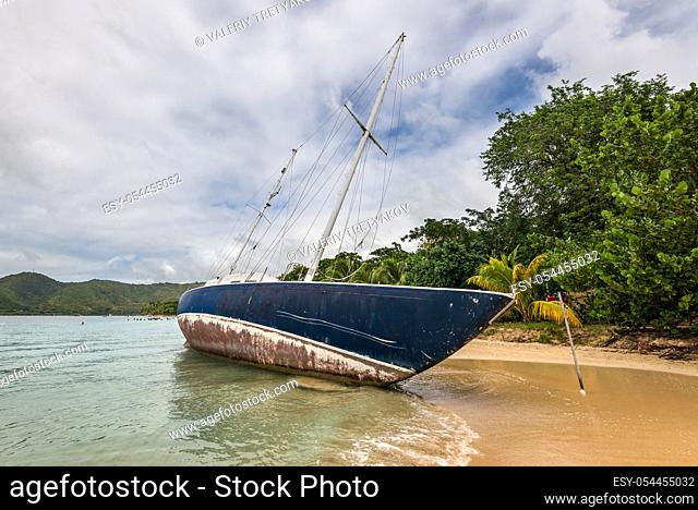 Abandoned beached sailboat after the hurrican Maria at the beautiful tourist beach at Sainte-Anne in Martinique, Caribean island in cloudy weather - ship wreck...