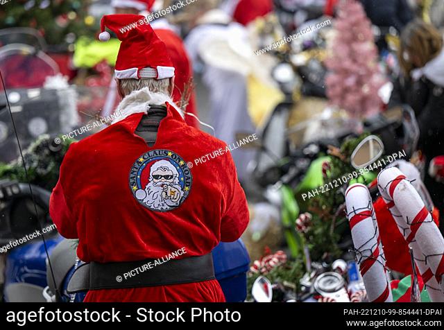 10 December 2022, Berlin: A participant in the ""Santa Claus on Road"" campaign stands next to his Christmas-decorated motorcycle