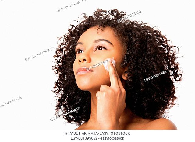 Beautiful young Brazilian woman applying massaging exfoliating anti-aging cream facial mask - skincare cosmetology - isolated