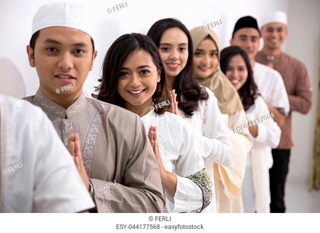 Group of muslim asian men and women smiling and greeting. embracing each other during eid mubarak celebration