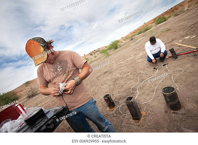 Two special effects workers setting up pyrotechnics in desert