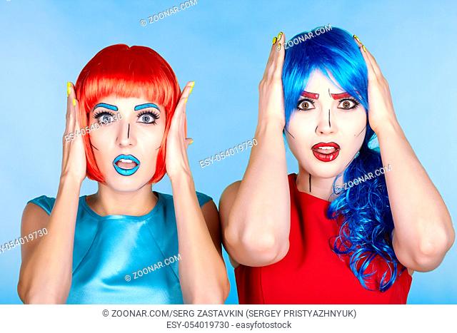 Portrait of young women in comic pop art make-up style. Shocked females in red and blue wigs and dresses