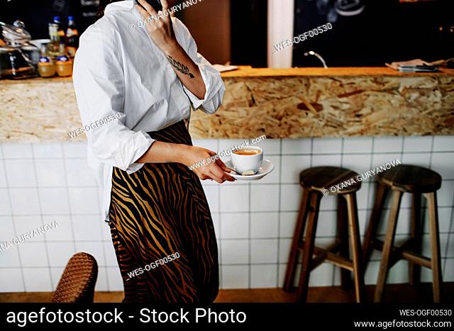 Female owner holding coffee cup while working in restaurant