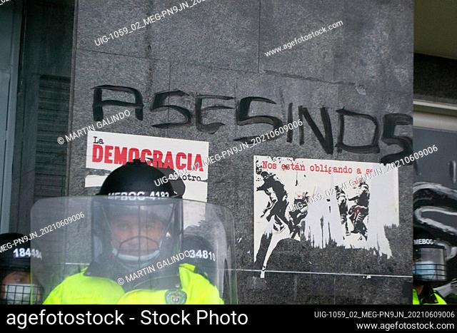 A police officer stands below a graffiti with the word ""Murders"" as demonstrations turned into clashes in southern Bogota at Portal de las Americas so-called...