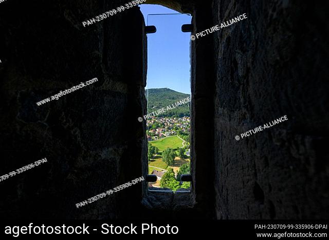 PRODUCTION - 06 July 2023, Saxony, Oybin: View through a window of the fortress and the monastery Oybin to the spa of the same name on the border with the Czech...