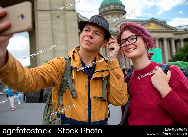 Young couple of tourists taking selfies against the Kazan cathedral in Saint Petersburg, Russia - close up